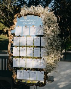 a wedding seating chart with flowers and greenery in front of a mirror on the wall