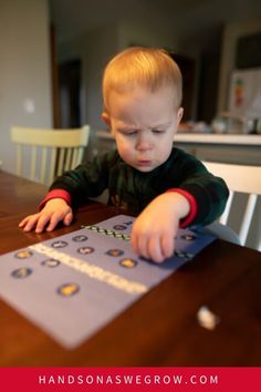 a young boy sitting at a table playing with some sort of magnets on it