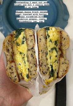 a person holding up a sandwich with eggs and spinach on it in front of a blue plate