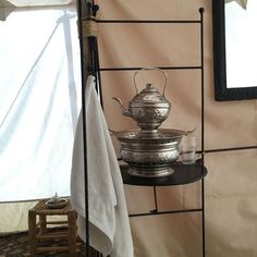 a metal tea pot sitting on top of a shelf next to a mirror and towel