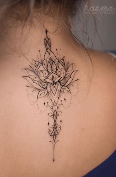 the back of a woman's neck with an intricate tattoo design on her left shoulder