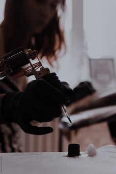 a woman in black gloves writing on a piece of paper with a pen and ink roller