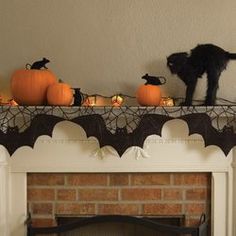 a black cat sitting on top of a mantle next to pumpkins and other decorations