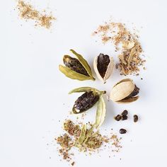 several different types of spices on a white surface, including cardamoa and pistachio