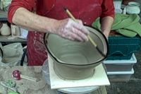 a man is working on a pottery bowl