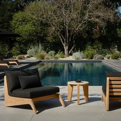 two wooden chairs sitting next to a swimming pool