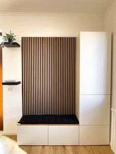 an empty room with a bench and wooden slats on the wall, next to a planter