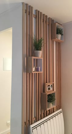 the wall is made out of wooden slats and has plants in them on shelves