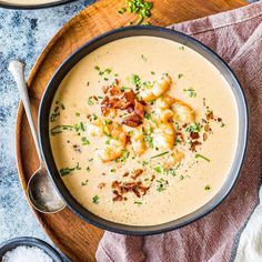 a bowl filled with soup on top of a wooden cutting board next to a spoon