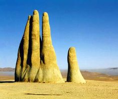 two large rocks in the desert with one hand extended up to the ground and another on top of it