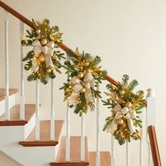 christmas garland on the banisters with gold and white bows hanging from it's handrail