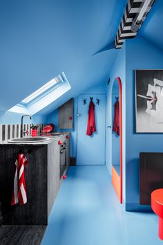 an attic kitchen with blue walls and orange stools on the countertop, painted in bright colors