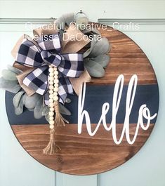 a wooden sign with the word hello painted on it and a bow attached to it