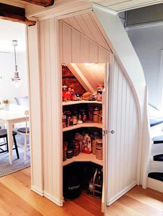 an open pantry in the corner of a room with wooden flooring and white walls