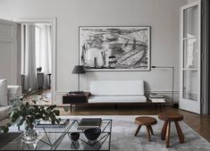 a living room filled with furniture and a painting on the wall above it's coffee table