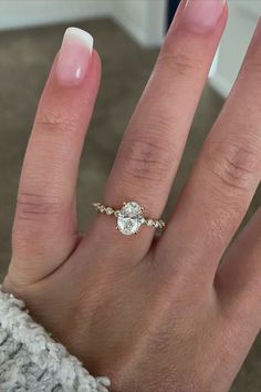 a woman's hand with a diamond ring on her left hand, and the other hand holding an engagement ring