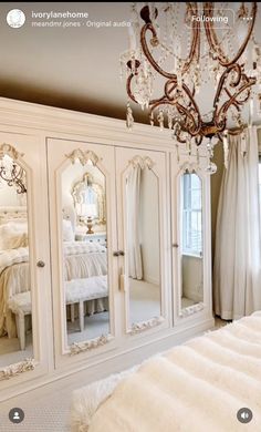 an ornate white armoire with mirrors and chandelier