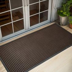 a brown door mat sitting on top of a wooden floor next to a glass door