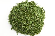 a pile of green herbs on a white surface