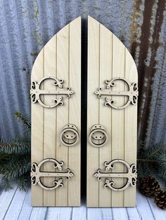 two wooden doors with metal handles are shown in front of pine cones and evergreens