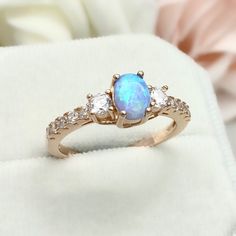 This beautiful ring is made from genuine 925 sterling silver with rose gold plating. Ring details- -The Main stone is an oval cut 7mm by 5mm Lab Created Light Blue Opal Stone  -Side stones are round 3mm and 1.5 clear simulated diamonds  -Ring is casted in solid 925 sterling silver with rose gold plating (yellow gold and rhodium plated also available, please check the drop down menu for more options) -The Total face height of the ring measures 7mms and the band width measures 2mms -Each ring is h Rose Gold Oval Opal Promise Ring, Oval Rose Gold Opal Ring For Anniversary, Rose Gold Oval Crystal Ring With Birthstone, Oval Rose Gold Crystal Ring With Birthstone, Rose Gold Oval Promise Ring, Oval Rose Gold Crystal Ring With Accent Stones, Oval Rose Gold Birthstone Ring, Rose Gold Oval Birthstone Ring, Oval Rose Gold Promise Ring