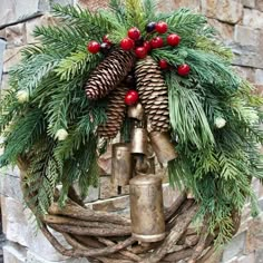 a christmas wreath with bells and pine cones on it, hanging from a stone wall