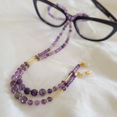 Beautiful, dainty, and luxurious. This amethyst eyeglass chain will complement your favorite pair of eyeglasses or sunglasses. *This eyeglass chain is approx. 26 inches.   *Made with faceted amethyst beads in 2 sizes,  permagold  seed beads, Swarovski crystals and gold plated tubes . *Featuring gold plated clasps and jewelry wire.  *includes 1 pair of clear with gold eyeglass loops AND 1 pair of black with gold eyeglass loops  This chain is a head turner! Elegant Handmade Glasses Chain For Everyday, Elegant Adjustable Glasses Chains As Gift, Elegant Glasses Chains As A Gift, Elegant Adjustable Glasses Chains For Gifts, Adjustable Purple Glass Glasses Chains, Purple Glass Glasses Chains As Gift, Beaded Eyeglass Chain, Sunglass Chain, Eyeglass Chain