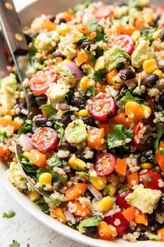 a white bowl filled with salad and a spoon on top of the bowl is sitting next to it