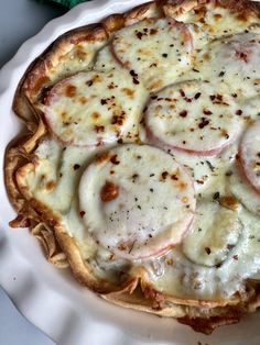 a white plate topped with a pizza covered in cheese