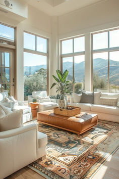 a living room filled with lots of white furniture and large windows overlooking the mountain range