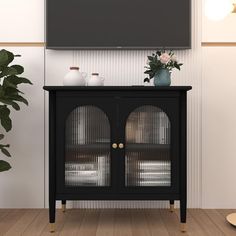 a black cabinet with two glass doors in front of a flat screen tv