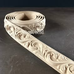 an intricately carved piece of wood on a black surface with the edge cut out