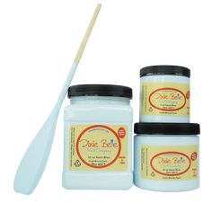 three jars of white paint and a wooden spoon