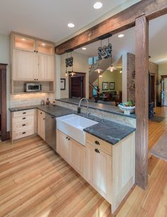 a large kitchen with wooden floors and white cabinets is pictured in this image from the doorway looking into the living room