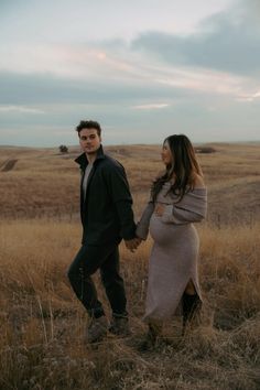 a pregnant couple holding hands in a field