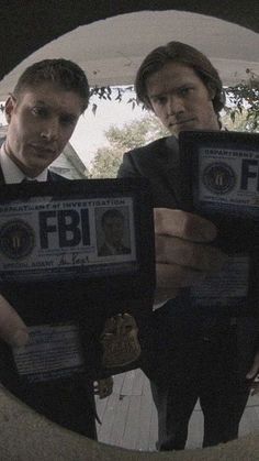 two men are holding up their id badges in front of a circular hole that has the words fbf on it