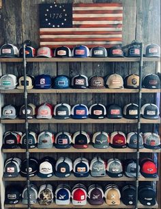 many hats are lined up on shelves in front of an american flag and wooden planks