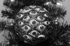 an ornament with eyes on it is hanging from a christmas tree in black and white