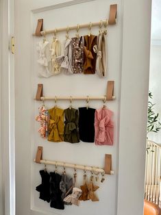 there is a wall hanging rack with baby clothes on it and two wooden pegs