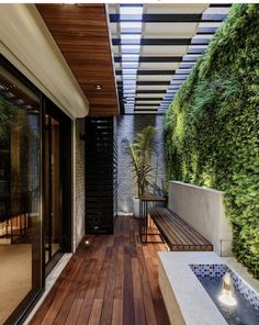 an outdoor area with wooden flooring and plants on the wall, along with a water feature