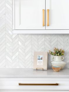 a white kitchen with herringbone tile backsplash