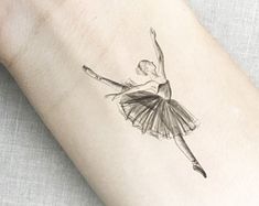 a ballerina tattoo on the left inner forearm and wrist is shown in black ink