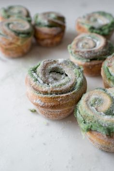 several pastries with green and white frosting on top of a marble countertop