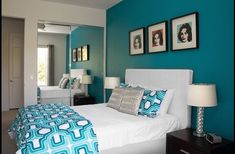 a bedroom with blue walls and pictures on the wall above the bed, along with two nightstands