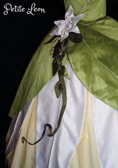 the dress is green and white with a flower on it's back, along with leaves