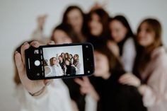 a woman taking a photo with her cell phone while others are behind her in the background