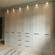 a large white closet with many drawers and lights on the wall above it, along with an area rug