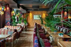 the interior of a restaurant with colorfully decorated tables and chairs, plants in vases