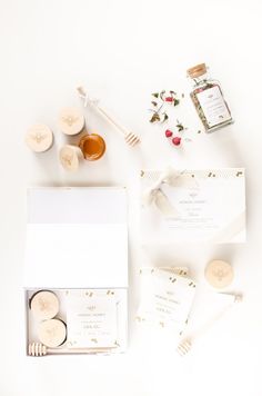 the contents of a wedding suite laid out on a white surface with flowers and honey