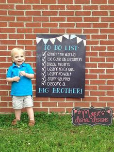 a little boy standing in front of a brick wall next to a big brother sign